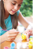 Young girl painting Easter eggs at a table outdoors